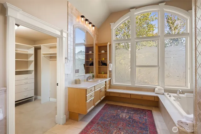 a bathroom with a tub a sink and a large window