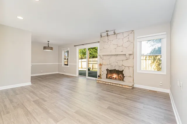 an empty room with windows a fireplace and wooden floor