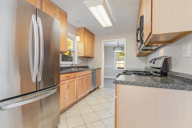 a kitchen with stainless steel appliances granite countertop a refrigerator a sink and white cabinets
