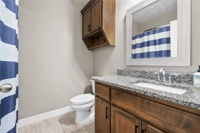 a bathroom with a granite countertop toilet sink and mirror