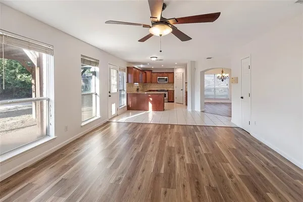 a view of a livingroom with wooden floor a ceiling fan and windows