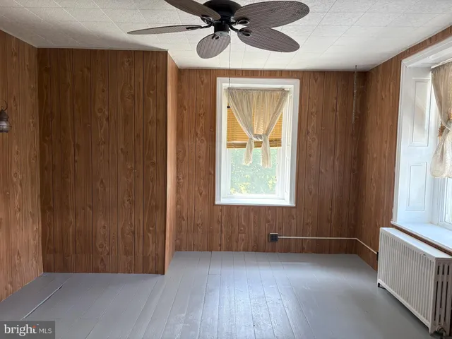 an empty room with windows and fan