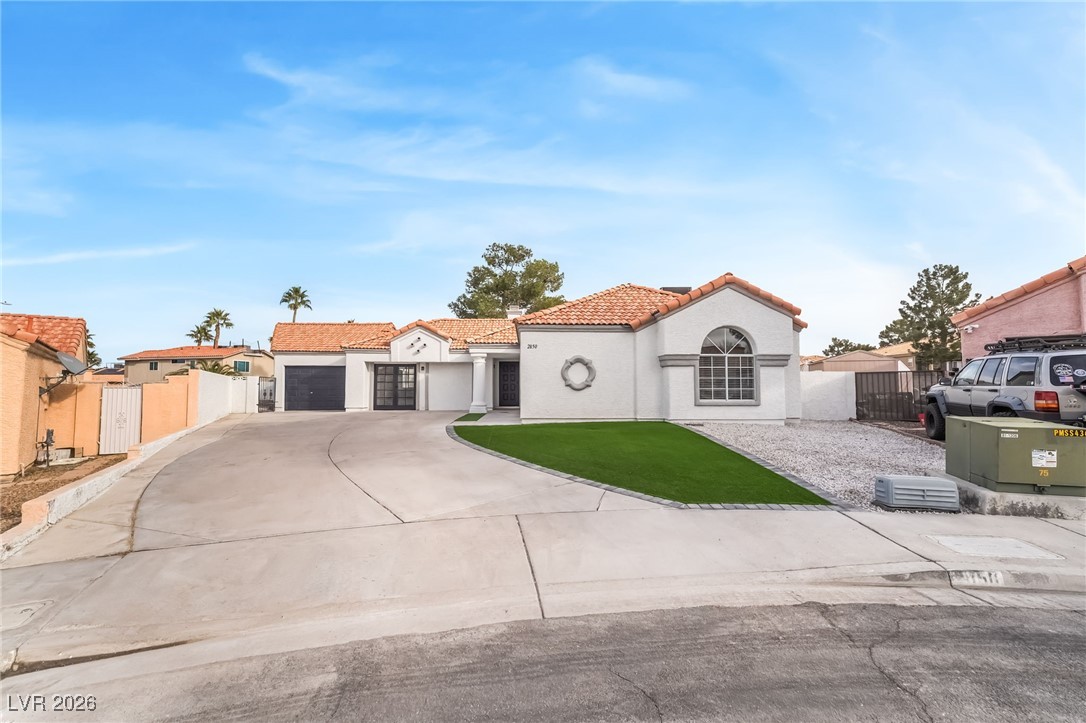Mediterranean / spanish-style home with concrete driveway, a gate, a tile roof, stucco siding, and an attached garage