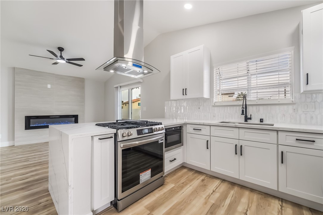 2850 Nikki Place Henderson, NV 89074 - Photo 11 of 64 Kitchen featuring tasteful backsplash, stainless steel gas range, a peninsula, island exhaust hood, and a fireplace