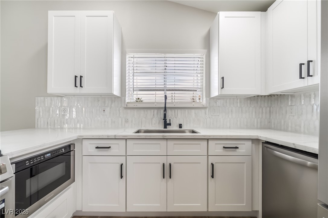 2850 Nikki Place Henderson, NV 89074 - Photo 13 of 64 Kitchen with stainless steel appliances, white cabinetry, light stone countertops, and decorative backsplash