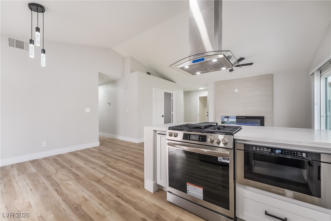 2850 Nikki Place Henderson, NV 89074 - Photo 14 of 64 Kitchen featuring appliances with stainless steel finishes, ventilation hood, decorative light fixtures, light wood-style floors, and white cabinets