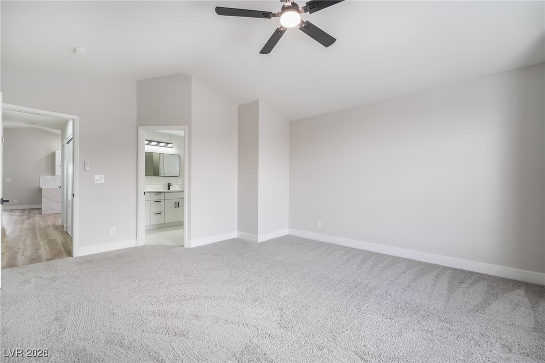 2850 Nikki Place Henderson, NV 89074 - Photo 17 of 64 Unfurnished bedroom with light colored carpet, lofted ceiling, connected bathroom, and ceiling fan