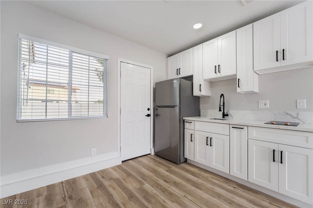 2850 Nikki Place Henderson, NV 89074 - Photo 34 of 64 Kitchen with white cabinetry, freestanding refrigerator, light wood-style flooring, light stone counters, and recessed lighting