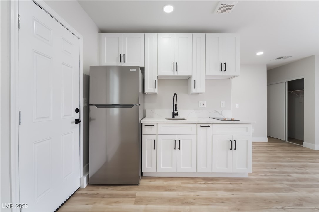 2850 Nikki Place Henderson, NV 89074 - Photo 35 of 64 Kitchen with freestanding refrigerator, recessed lighting, white cabinetry, and light wood-style flooring
