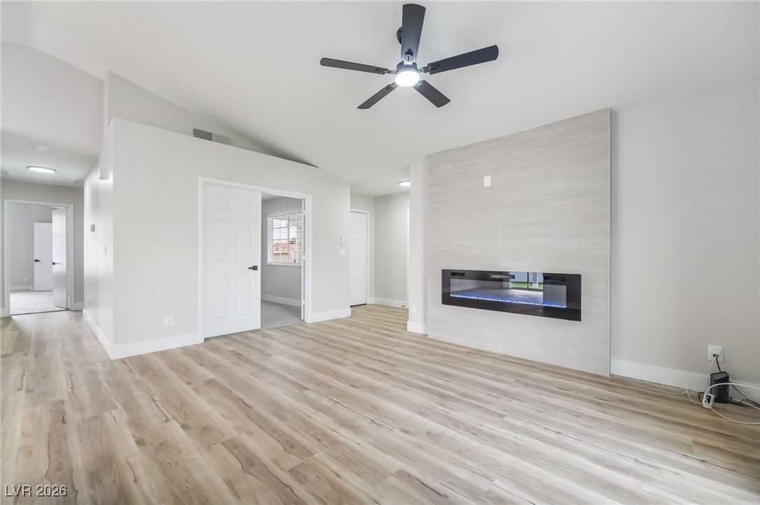 2850 Nikki Place Henderson, NV 89074 - Photo 8 of 64 Unfurnished living room with a fireplace, light wood-type flooring, vaulted ceiling, and a ceiling fan