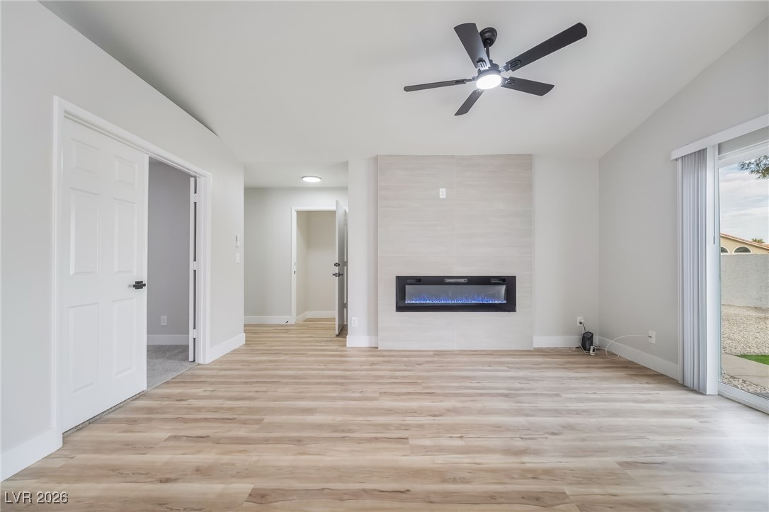 2850 Nikki Place Henderson, NV 89074 - Photo 9 of 64 Unfurnished living room featuring a large fireplace, light wood-style floors, and ceiling fan