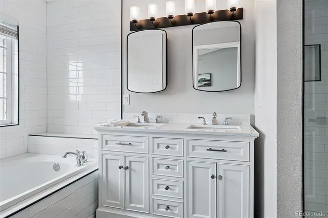 a bathroom with a double vanity sink and mirror with bathtub