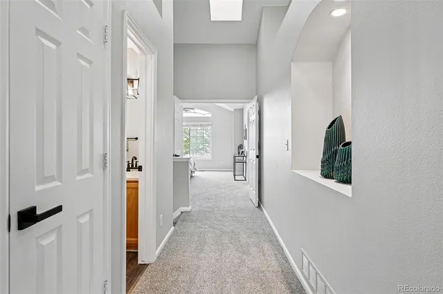 a view of a hallway with a livingroom and a bathroom with sink