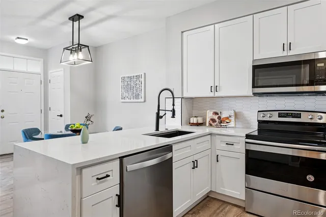 a kitchen with granite countertop a sink stainless steel appliances and white cabinets