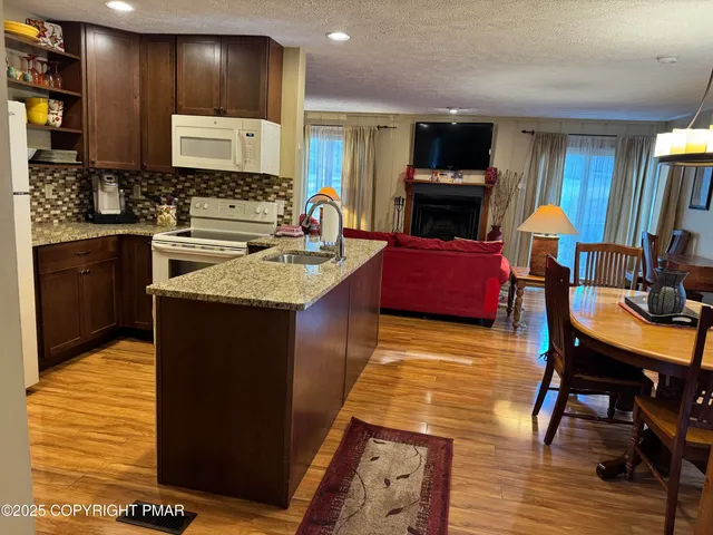 a kitchen with stainless steel appliances granite countertop a stove top oven a sink dishwasher a dining table and chairs with wooden floor