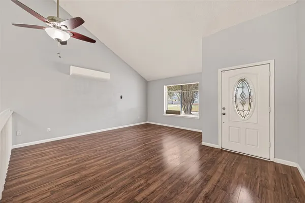 an empty room with wooden floor chandelier fan and windows