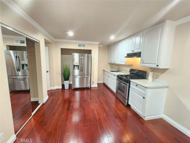 a kitchen with wooden floors appliances and cabinets
