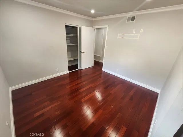 a view of an empty room with wooden floor and closet