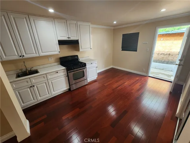 a kitchen with granite countertop wooden floors a sink and a stove