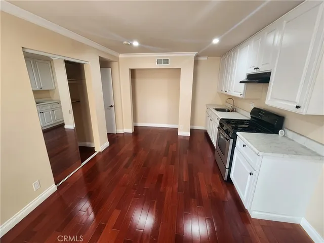 a view of a kitchen with wooden floor and electronic appliances