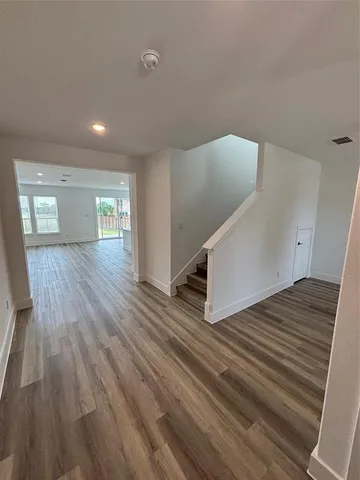 a view of an empty room with wooden floor and stairs