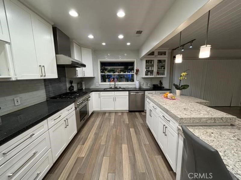 a large kitchen with stainless steel appliances granite countertop a stove sink and cabinets