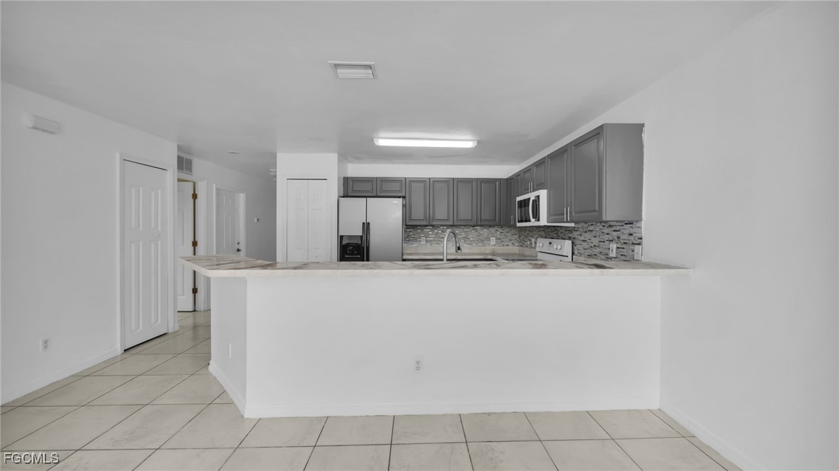 4551 22nd Street Southwest Lehigh Acres, FL 33973 - Photo 17 of 26 a view of kitchen with stainless steel appliances granite countertop a refrigerator a sink dishwasher and white cabinets with wooden floor