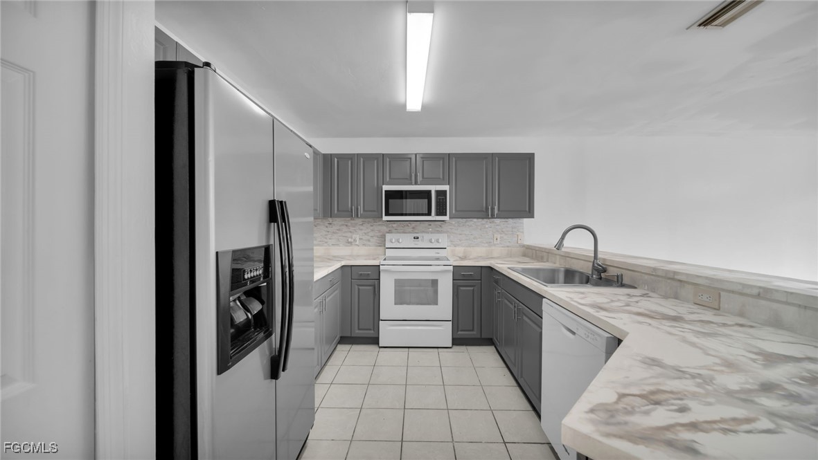 4551 22nd Street Southwest Lehigh Acres, FL 33973 - Photo 9 of 26 a kitchen with stainless steel appliances granite countertop a sink a stove top oven and a refrigerator