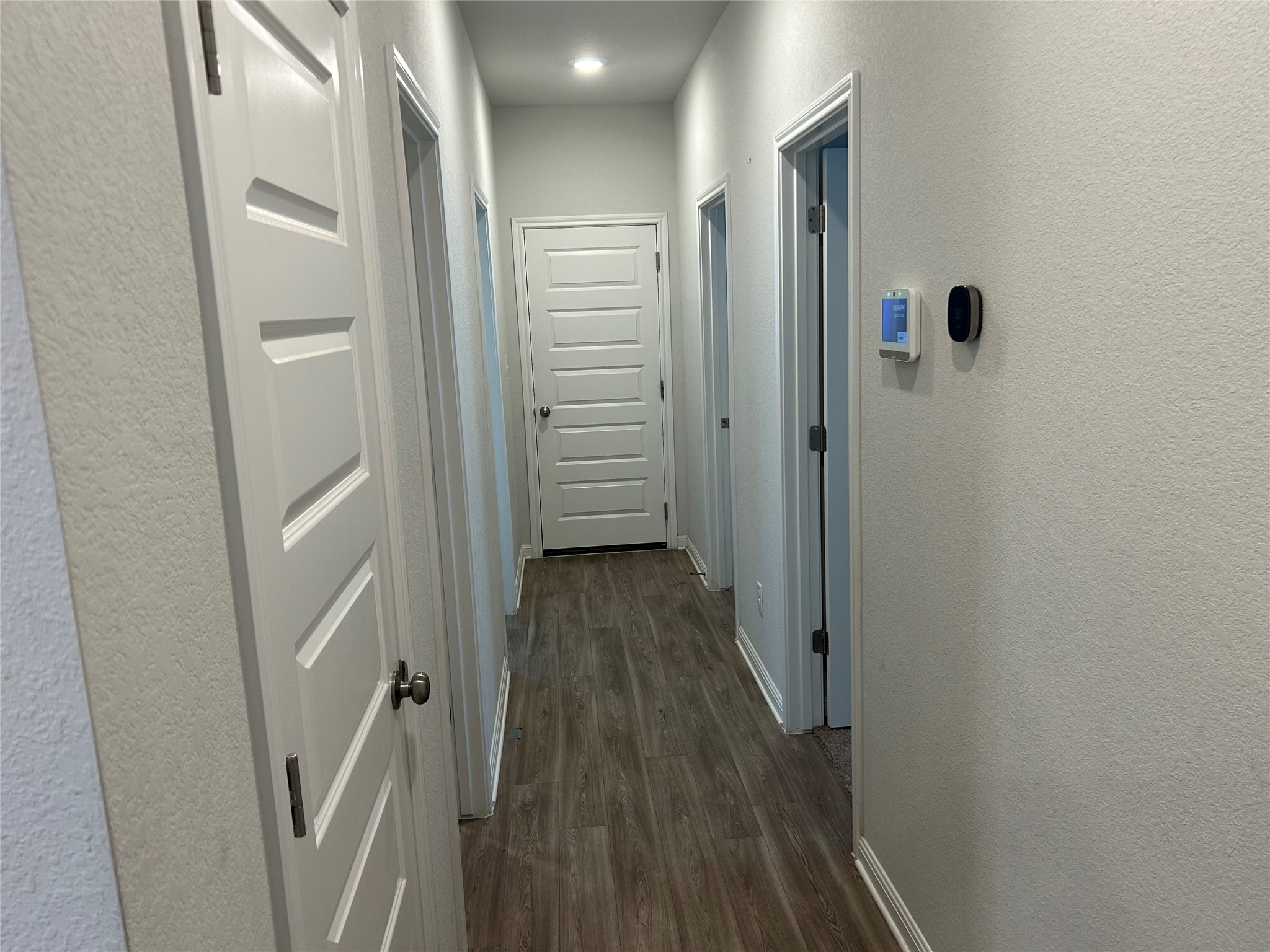 118 Two Bits Lane Elgin, TX 78621 - Photo 16 of 23 Smooth wood-look flooring guides the eye down a neutral hallway illuminated by recessed lighting.