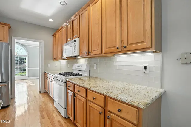 a kitchen with granite countertop cabinets stainless steel appliances a sink and wooden floor