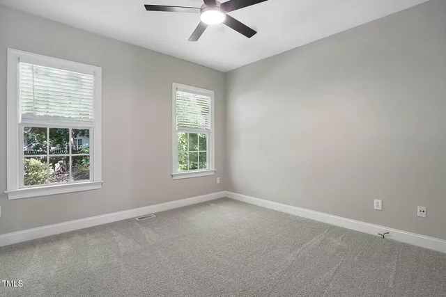 a view of a livingroom with a ceiling fan & windows