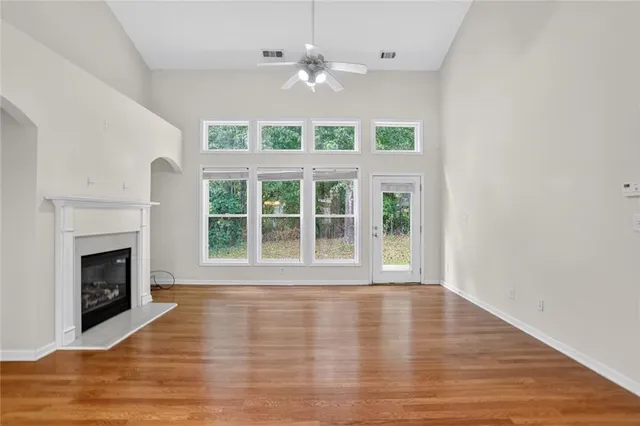 a view of an empty room with wooden floor and a fireplace