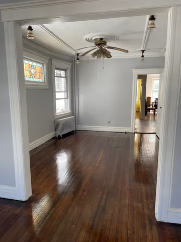 a view of empty room with wooden floor and fan