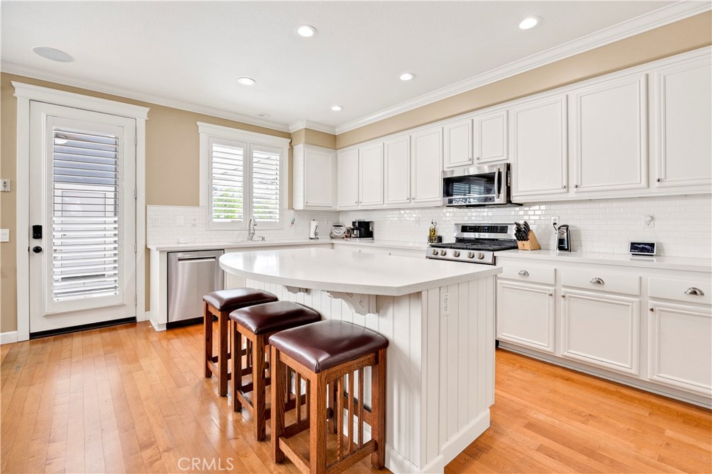 40152 Stowe Road Temecula, CA 92591 - Photo 13 of 56 a kitchen with stainless steel appliances granite countertop a stove a sink a microwave a refrigerator and white cabinets with wooden floor