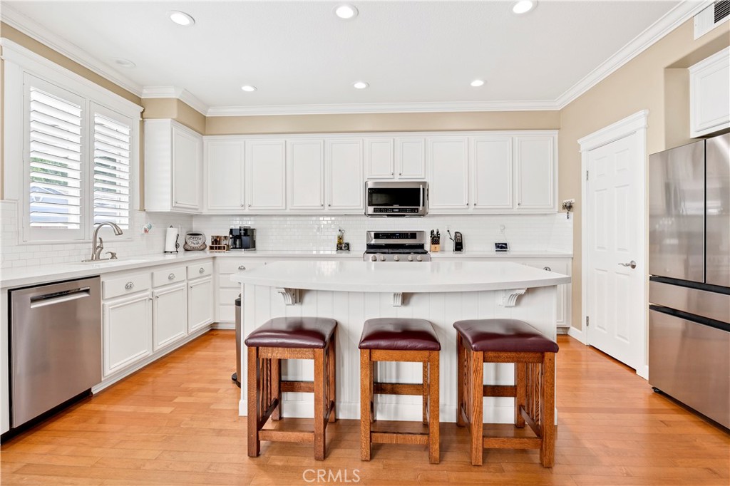 40152 Stowe Road Temecula, CA 92591 - Photo 14 of 56 a kitchen with stainless steel appliances granite countertop a white stove top oven a sink a refrigerator and white cabinets with wooden floor