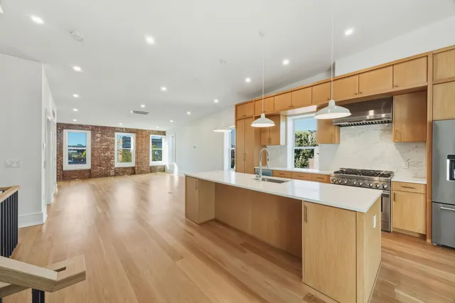 a large kitchen with stainless steel appliances a large counter top a stove and a refrigerator