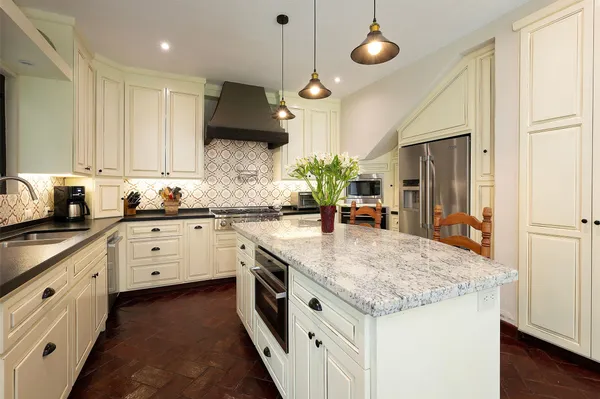 a kitchen with stainless steel appliances granite countertop a sink a stove and a wooden floors