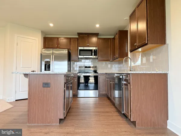 a kitchen with kitchen island granite countertop stainless steel appliances cabinets a sink and a counter top space
