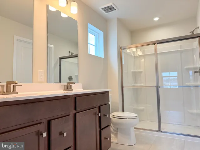 a bathroom with a double vanity sink toilet mirror and shower