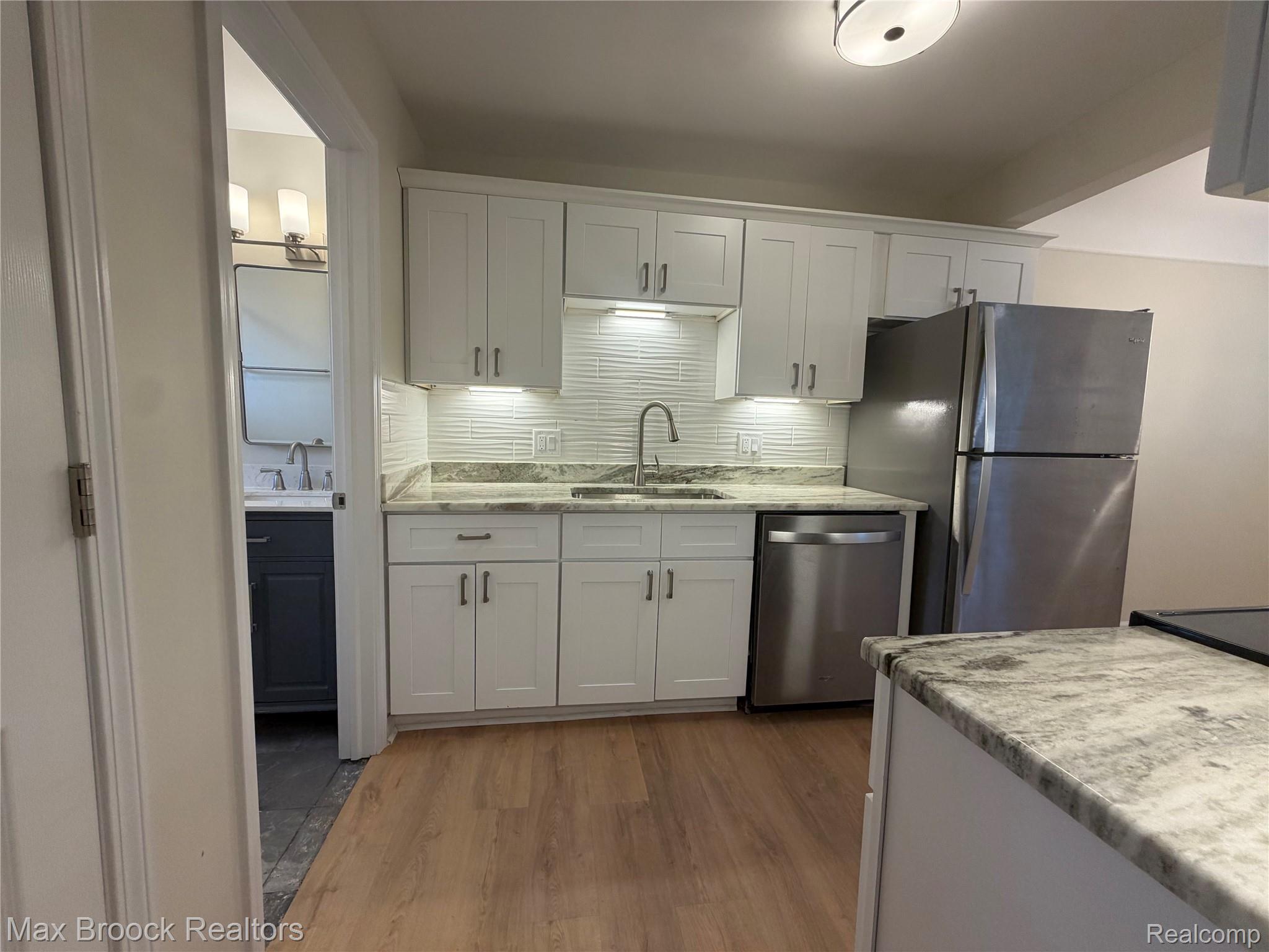 3875 Devon Road, Unit # 9 Royal Oak, MI 48073 - Photo 5 of 17 Modern kitchen featuring white shaker cabinetry, stainless steel appliances, and wood-finish flooring