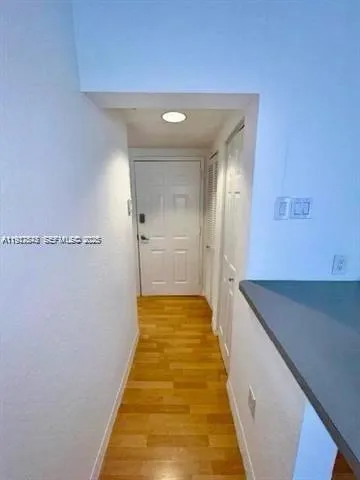 a hallway with white cabinets and wooden floor