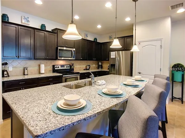 a kitchen with stainless steel appliances kitchen island granite countertop a dining table and chairs