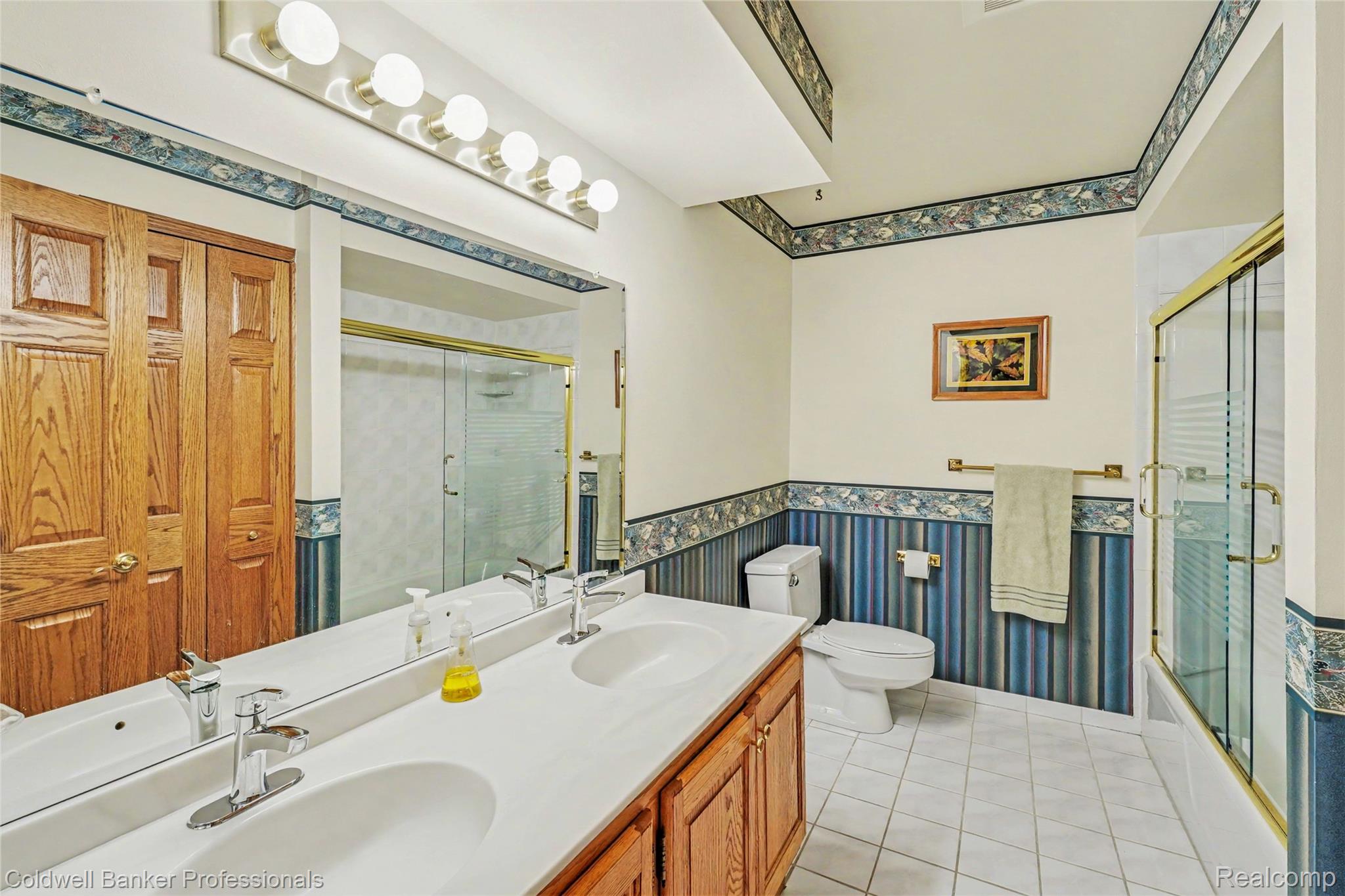 3583 Mitchell Road Metamora, MI 48455 - Photo 43 of 58 Bathroom featuring a dual-sink vanity with white countertops, a large wall-mounted mirror, white tile flooring, and a shower-tub combination with a glass enclosure