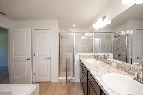 a bathroom with a granite countertop double vanity sink a mirror and shower