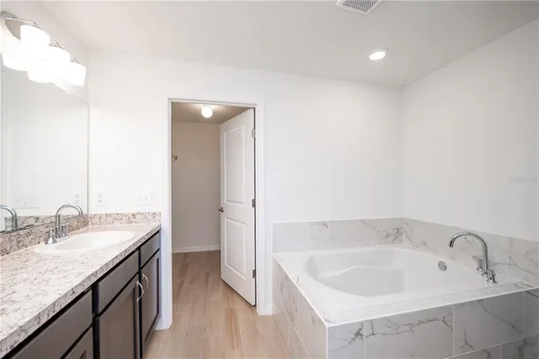 a spacious bathroom with a granite countertop sink and a bathtub