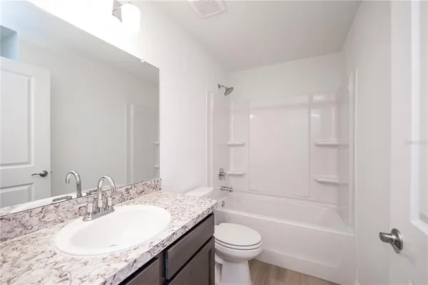 a bathroom with a granite countertop sink mirror toilet and bathtub