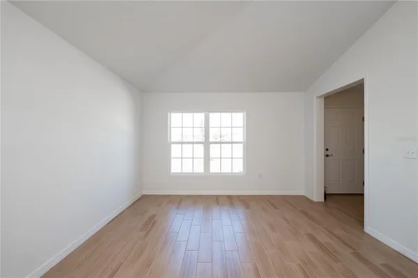 an empty room with wooden floor and window