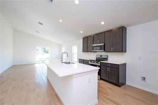a kitchen with stainless steel appliances granite countertop a sink stove microwave and refrigerator