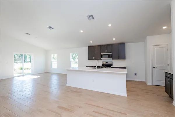 a open kitchen with granite countertop a stove top oven a sink dishwasher and a refrigerator with wooden floor