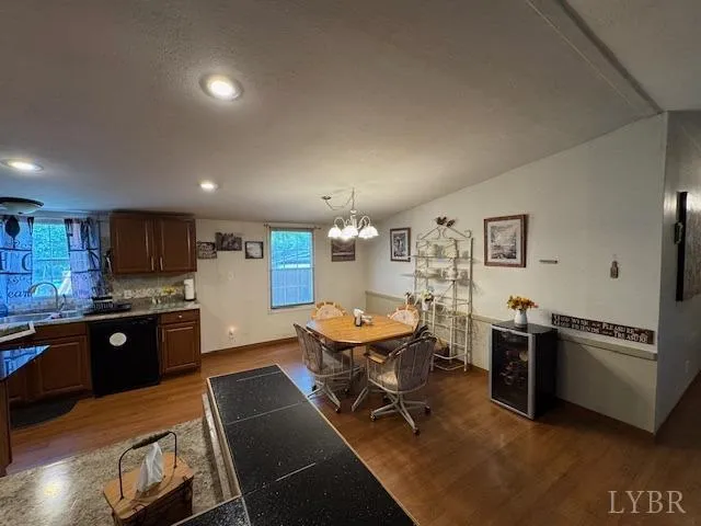 a kitchen with stainless steel appliances kitchen island granite countertop a refrigerator a stove a sink a dining table and chairs with wooden floor